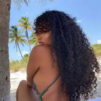 Model on a tropical vacation, hair styled in Island Curl loose curly hair extensions, showing off beach-ready hairstyles and humidity proof curls with frizz-control in humidity