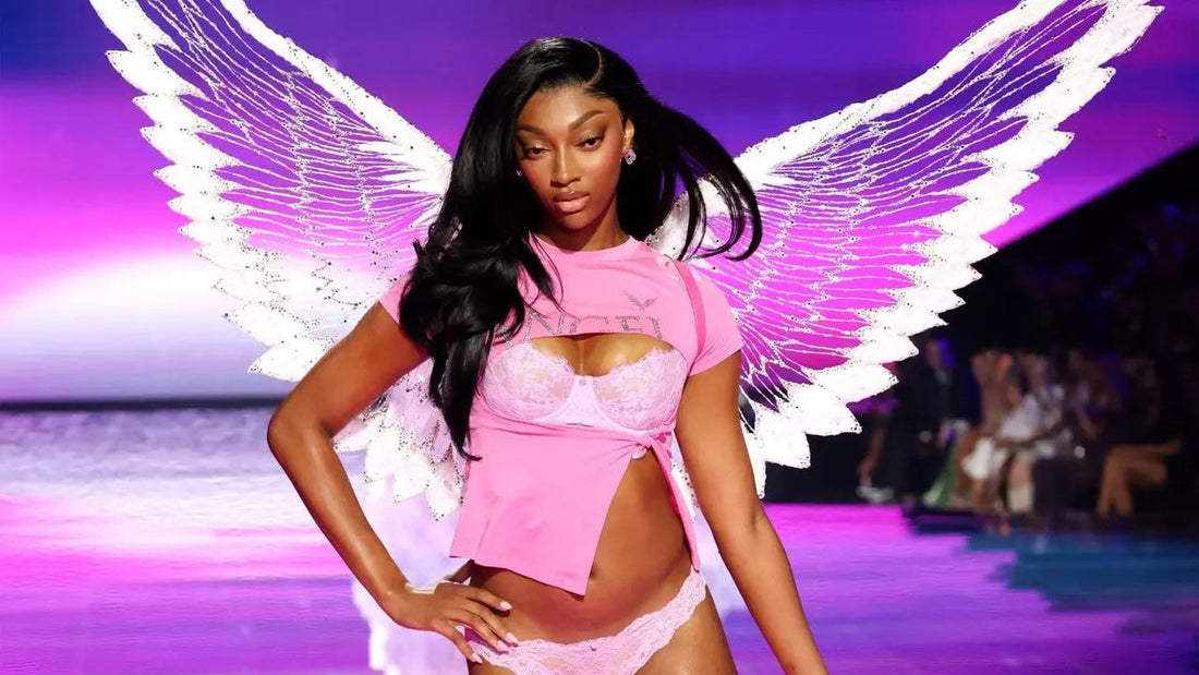 Angel Reese walking the 2025 Victoria’s Secret Fashion Show runway in a glamorous bombshell blowout, wearing sparkling angel wings and pink lace lingerie.
