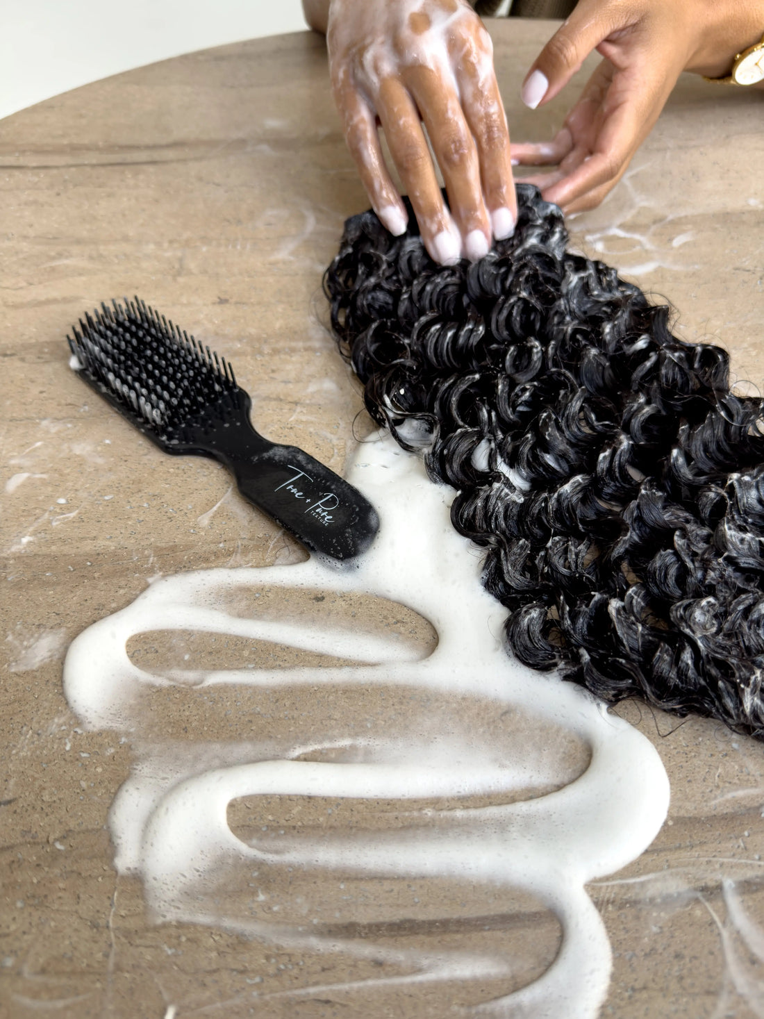 True + Pure Texture Hair Extensions Island Curl Type 3A loose curly wavy bundle being washed shampooed next to True + Pure Texture detangling brush - sensory natural hair visual