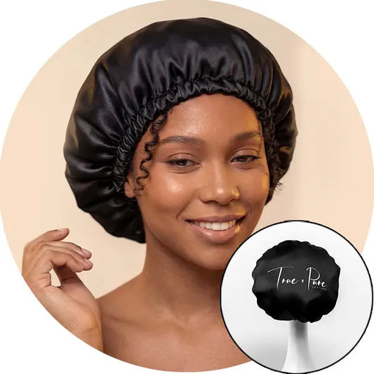 Woman wearing a black satin bonnet with 'True & Pure' logo inset.